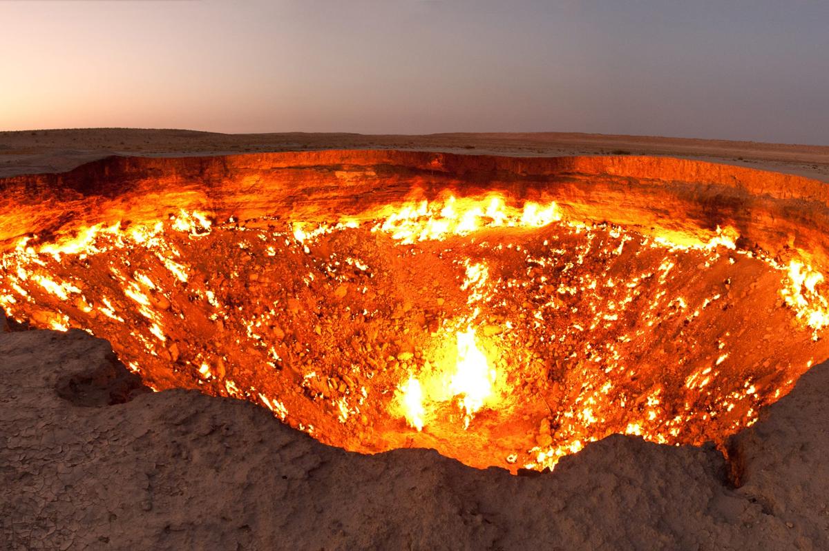 The whole Darvaza crater glowing at dusk with the desert around it
